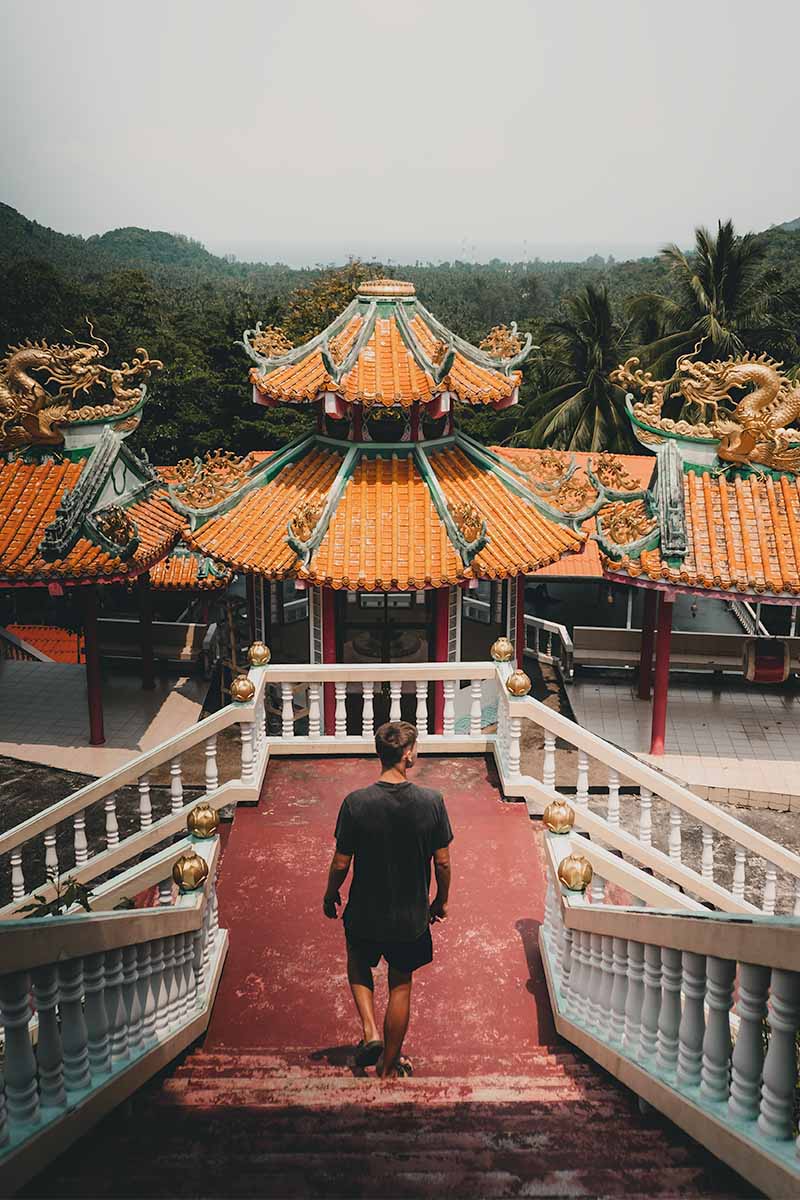A tourist walking down the faded, red coloured stairs at the Chinese Temple.