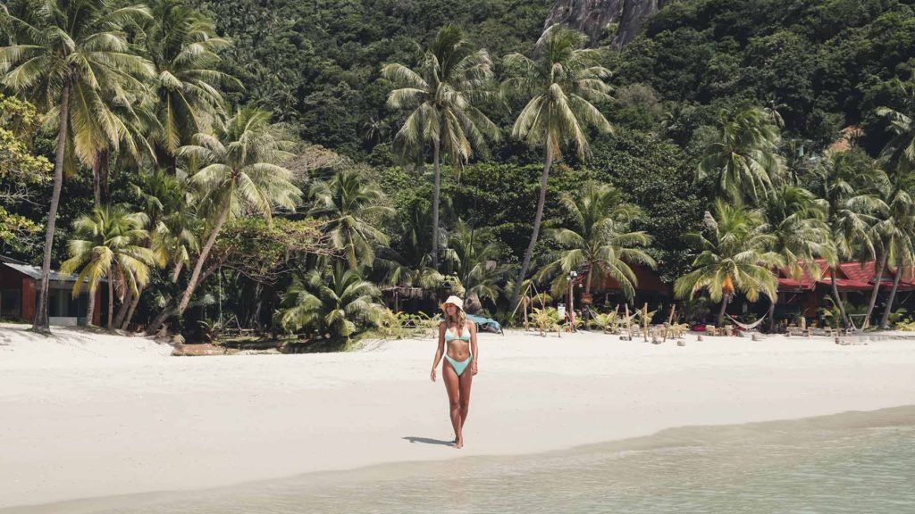 A tourist walking towards the water on Haad Rin Beach.