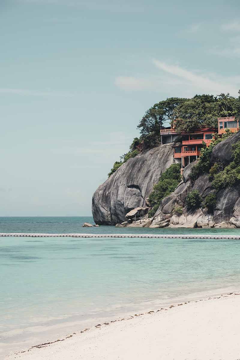 The calm, turquoise water and tall coastal boulders of Leela Beach.