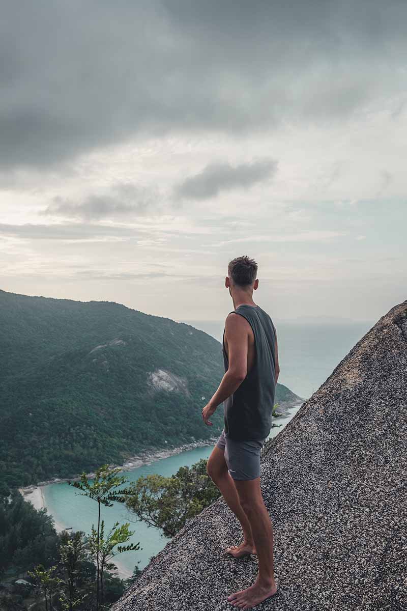 A tourist standing on a rock overlooking Bottle Beach below.