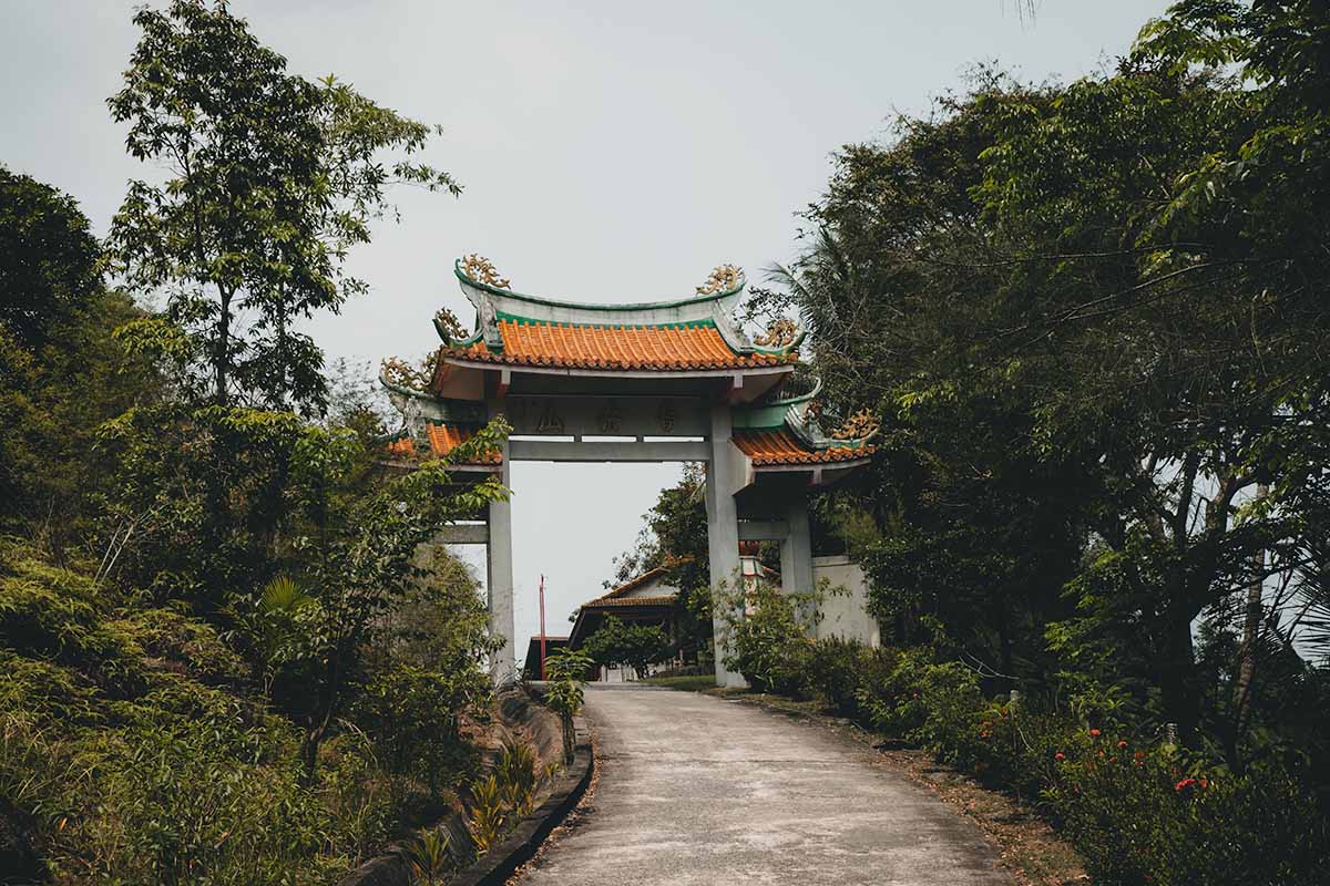 The road leading up to the Chinese Temple's bright orange and teal entrance gate.