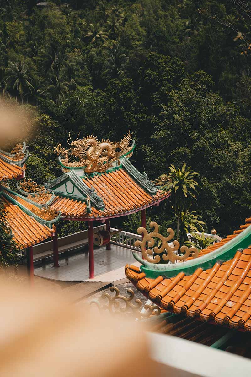 Some of the temple complex's bright orange and teal roofs with a gold dragon statue atop one.