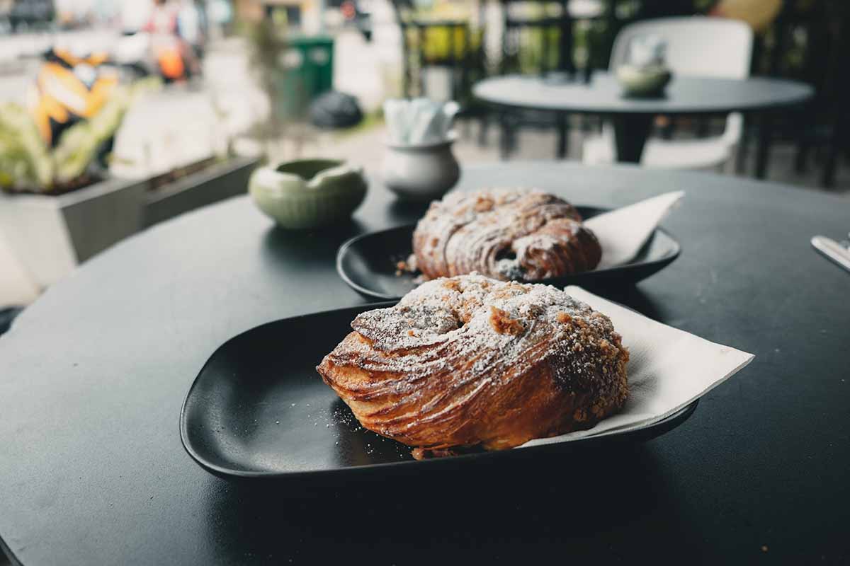 Two flour-topped chocolate croissant pastries served by the German Bakery.