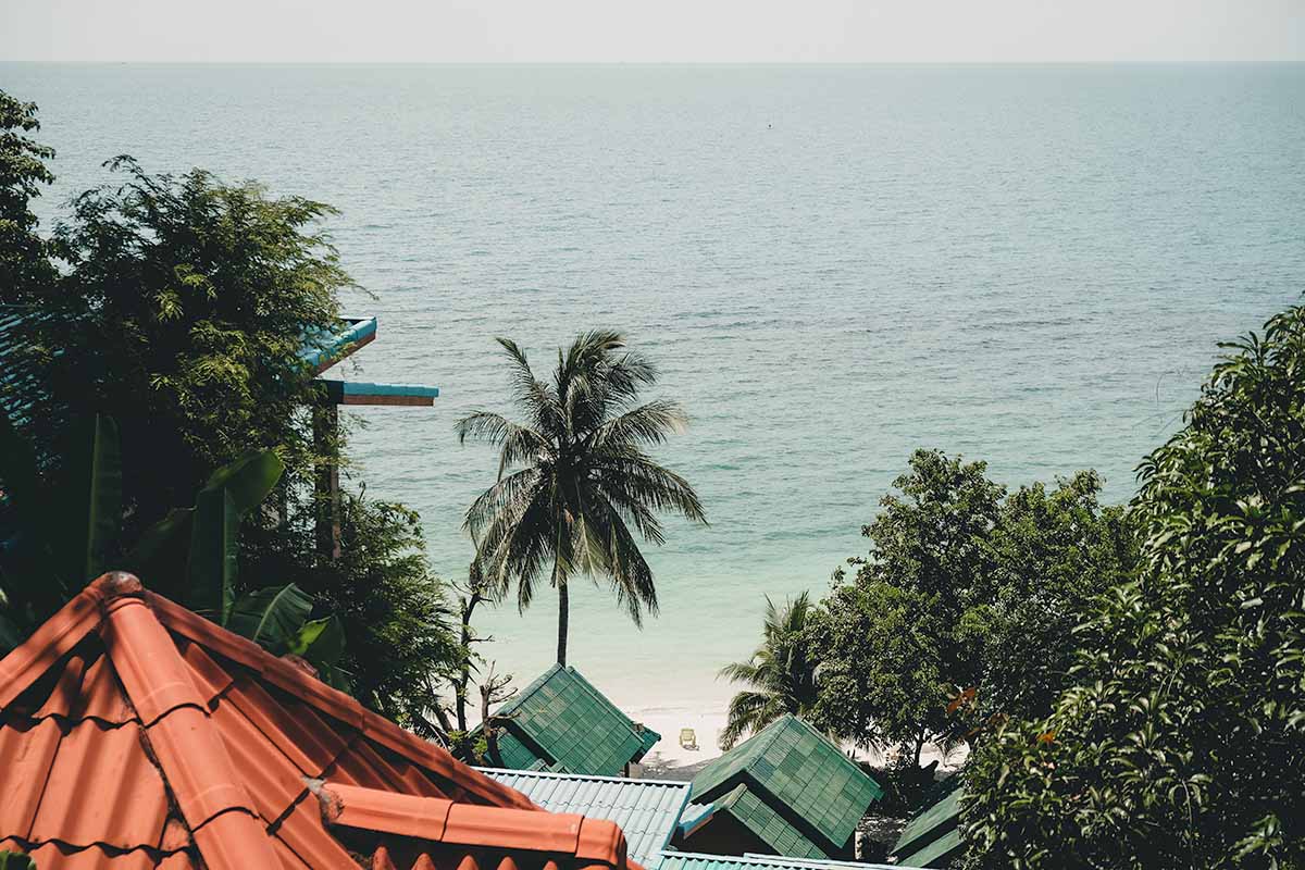 The lower level buildings and sand, sea and palm trees of Haad Yao as seen from the Whats Cup Cafe seating area above.