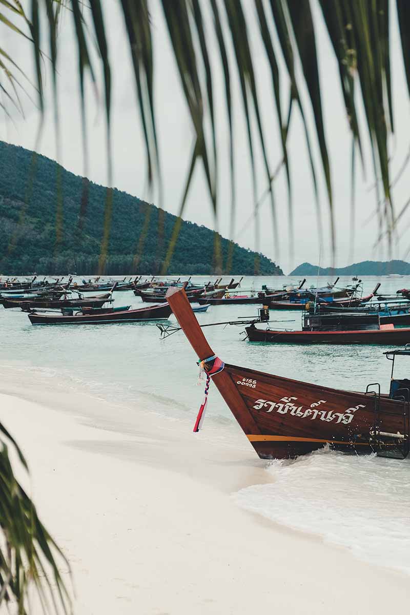 Many wooden long-tail boats lined up in the shallow waters of Sunrise Beach.