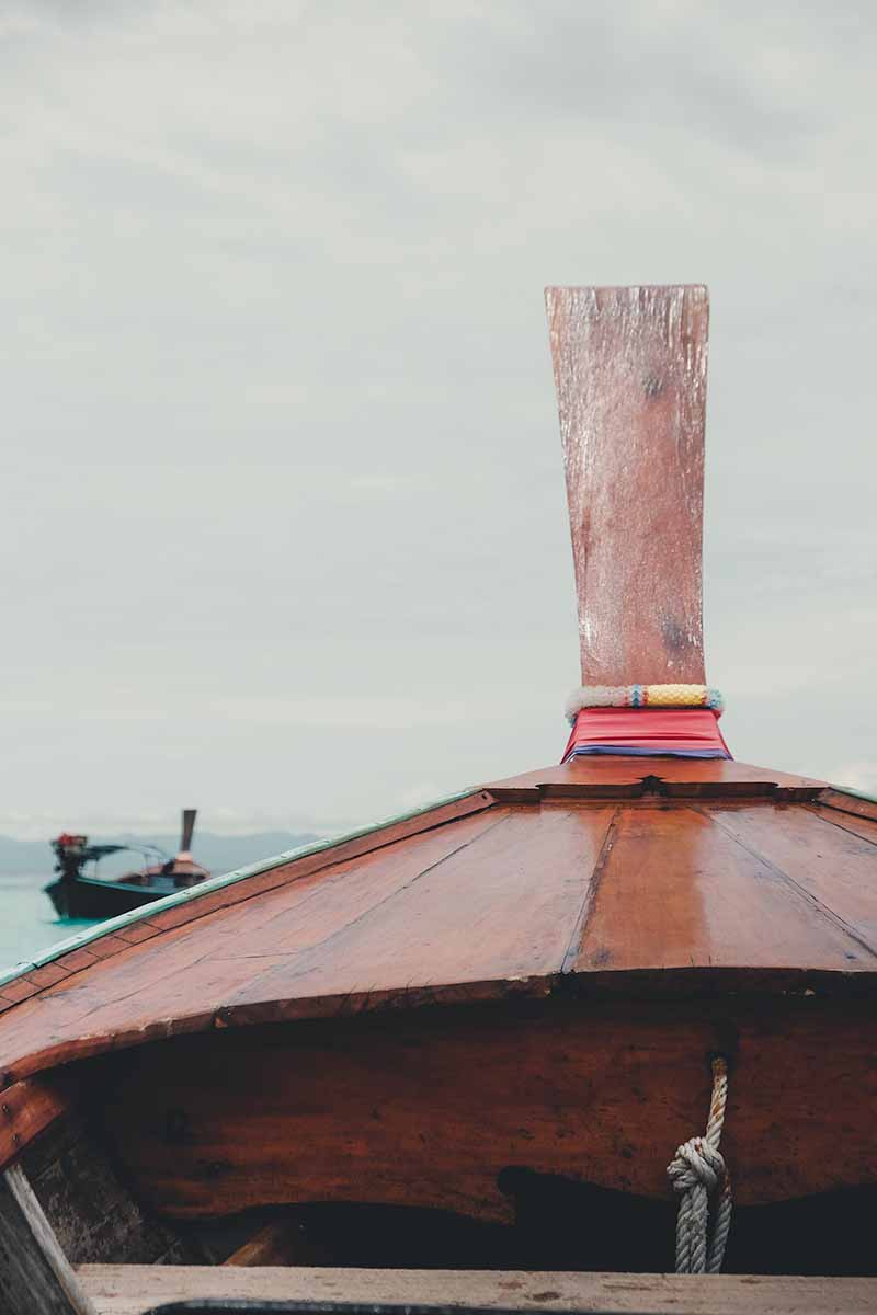 A close up of the wooden bow of a long-tail boat.