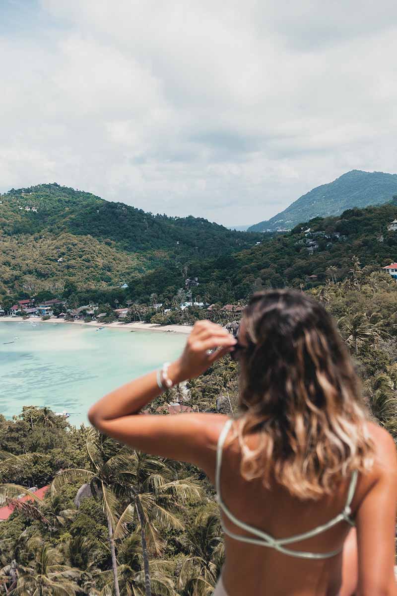 A female tourist sitting at John Suwan Viewpoint looking over Chalok Baan Kao Bay.