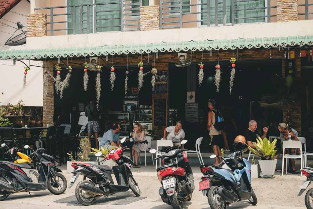 People sitting at outdoor, shaded tables at the front of the German Bakery by Achim.