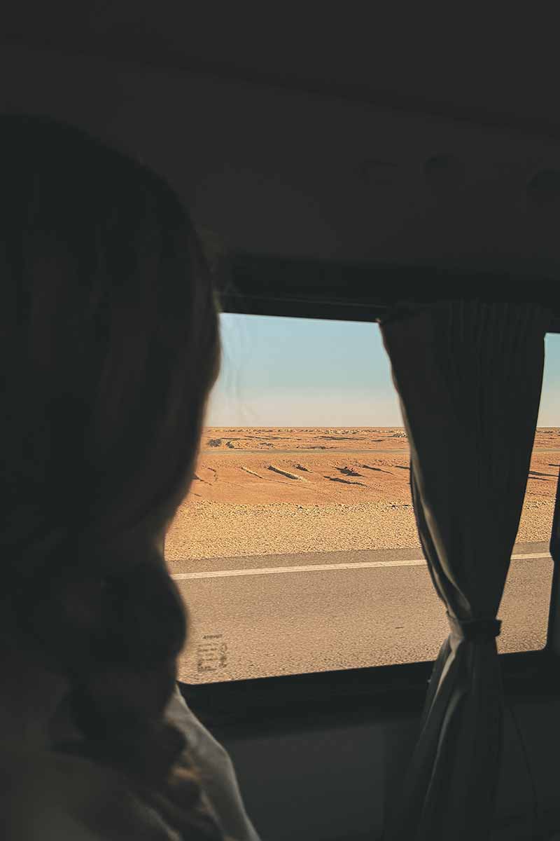 A person looking out of a microbus window at the vast arid landscape while en route to Siwa Oasis from Cairo.