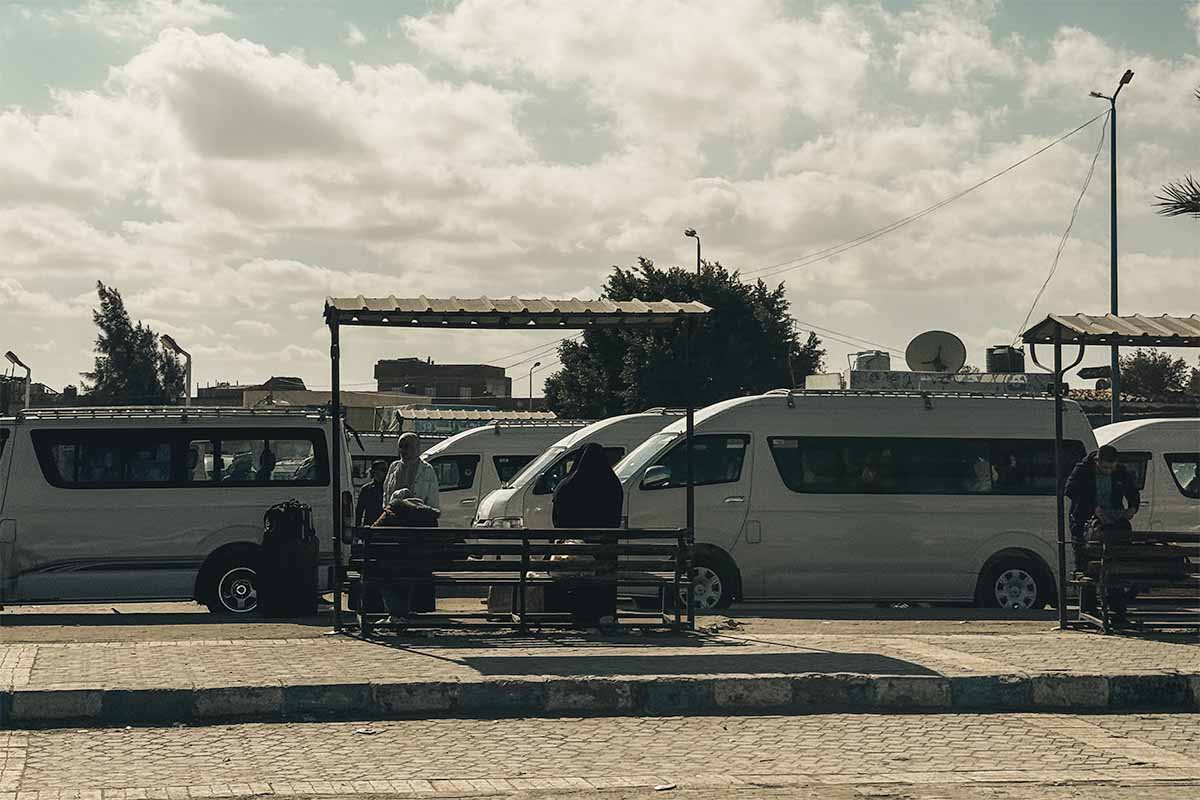 Two small bus shelters and several parked microbuses at the Marsa Matruh Microbus Station.