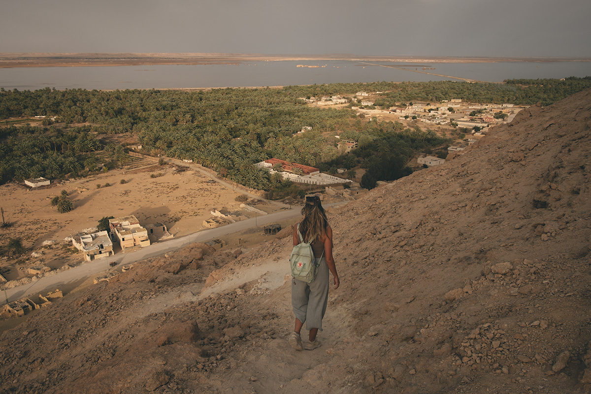 A woman carefully walking down Dakrur Mountain's dusty, gravel trail.