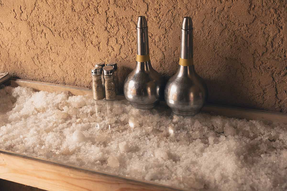 Various condiments sitting on a glass topped table which contains rock salt as decoration.