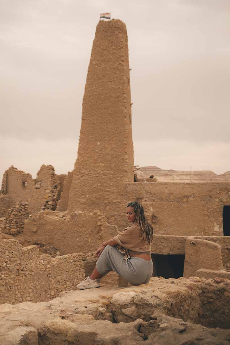 A woman sitting among the ruins of the Oracle Temple.