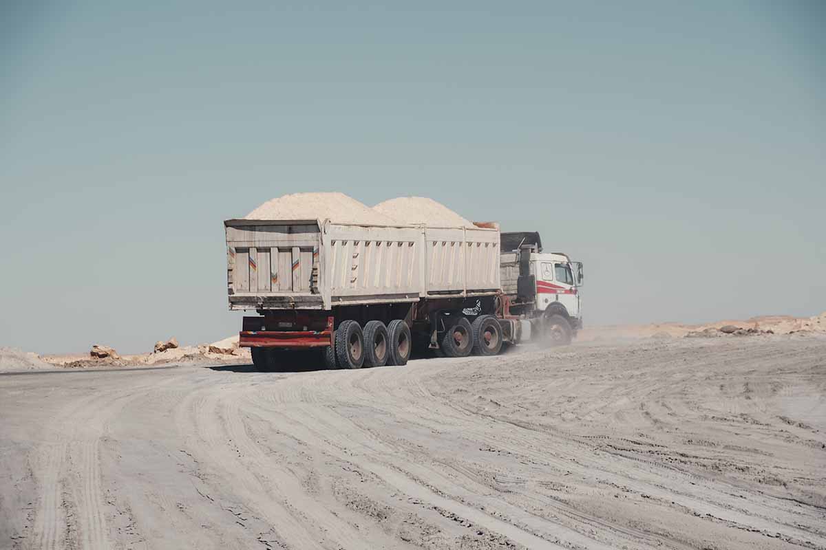 A truck towing a double trailer piled high with rock salt.