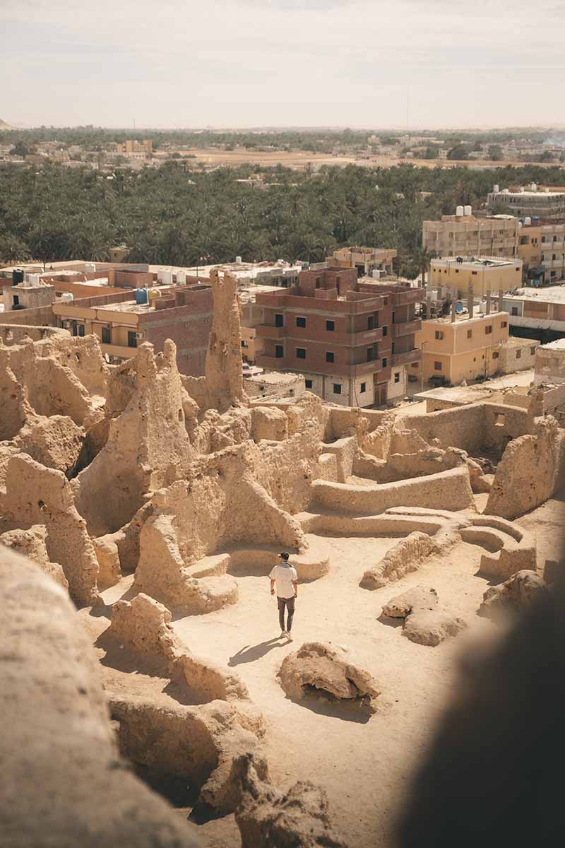 A person standing amongst the mud-brick ruins of Shali Fortress.