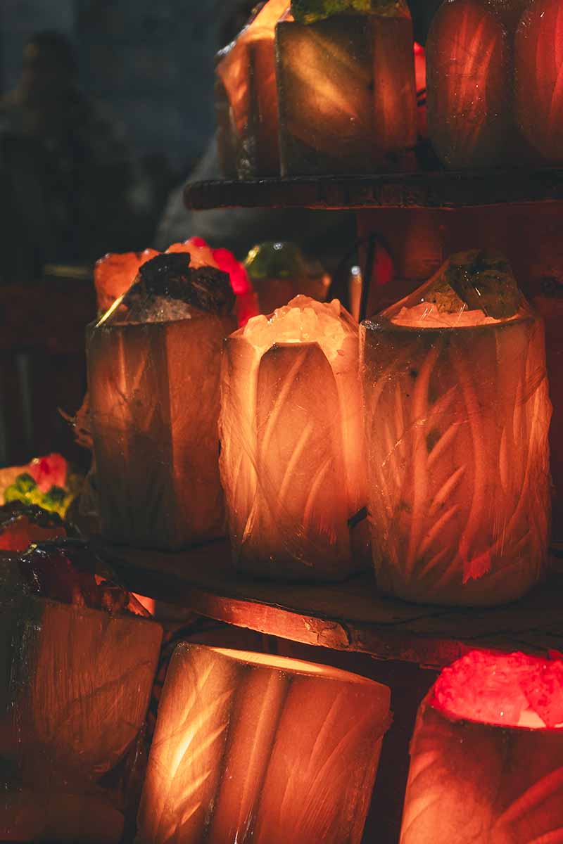 Three tiers of salt lamps glowing orange in the dark.