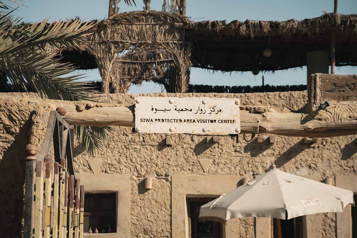 A small sign reading Siwa Protected Area Visitor Center in English and Arabic.