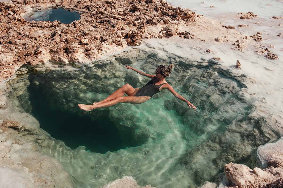 A woman floating in a small turquoise salt lake.