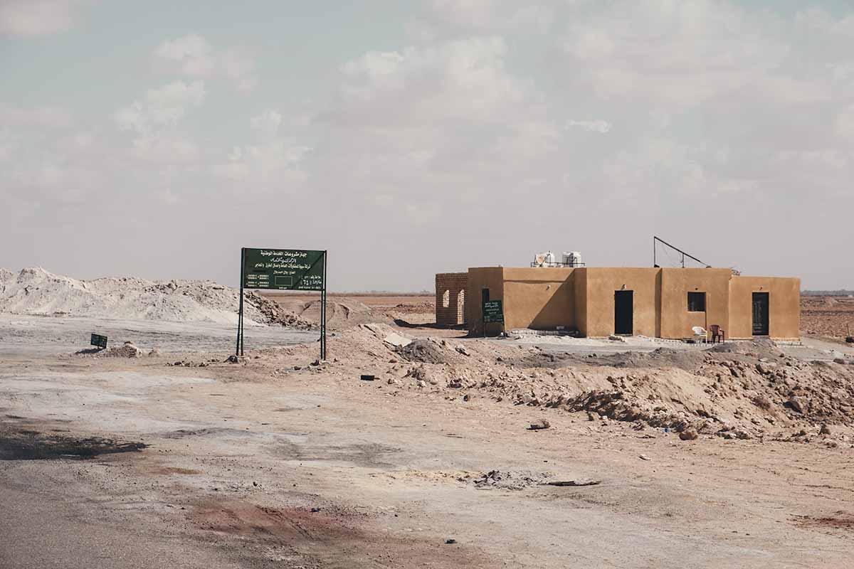 A sign and orange building marking the entrance to Siwa's salt mine.