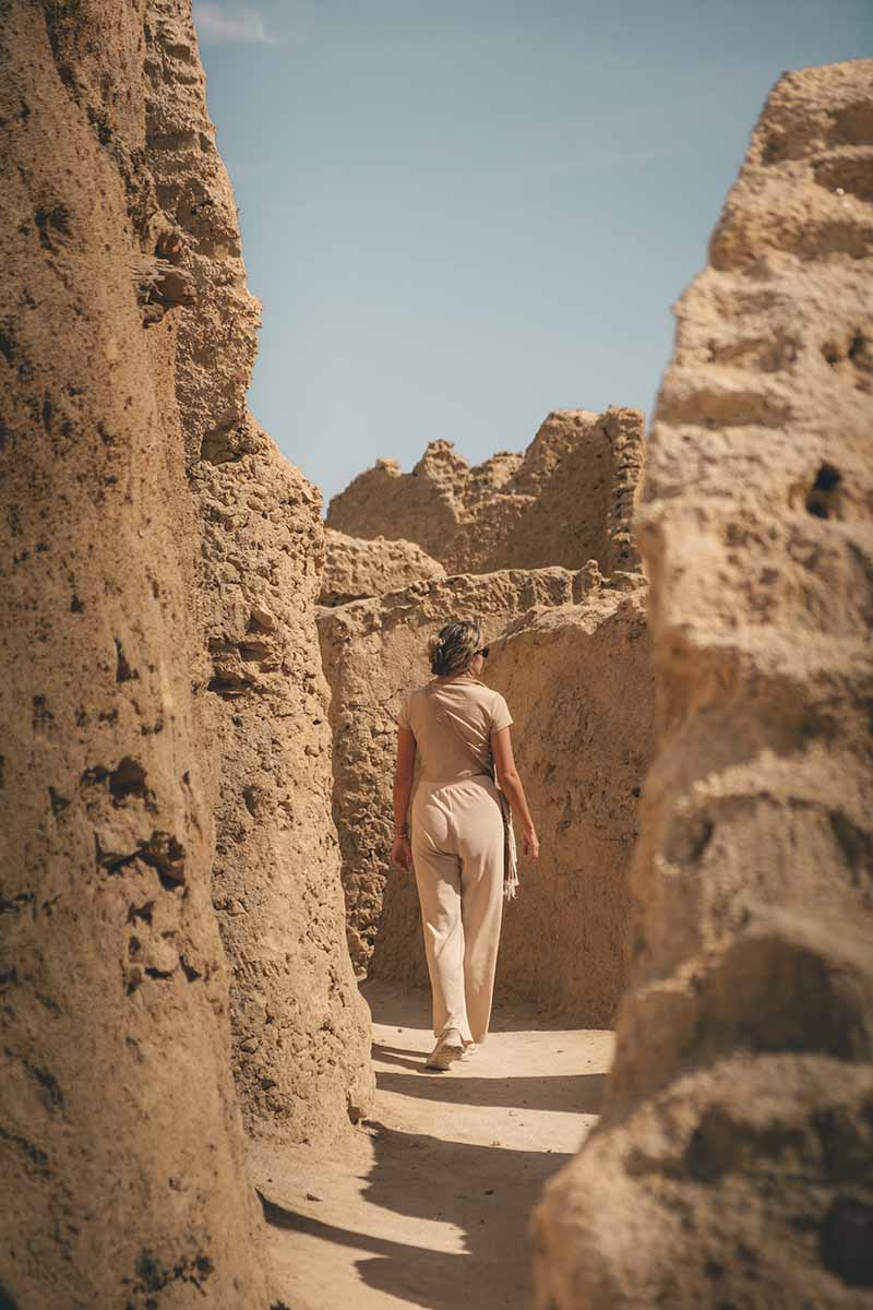 A woman walking through the narrow passageways of Shali Fortress.