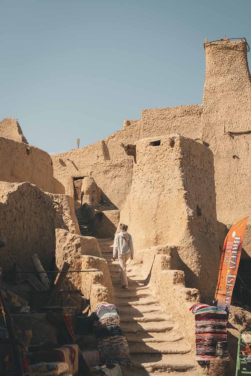 A woman walking up a set of steps that lead up to the entrance of Shali Fortress.