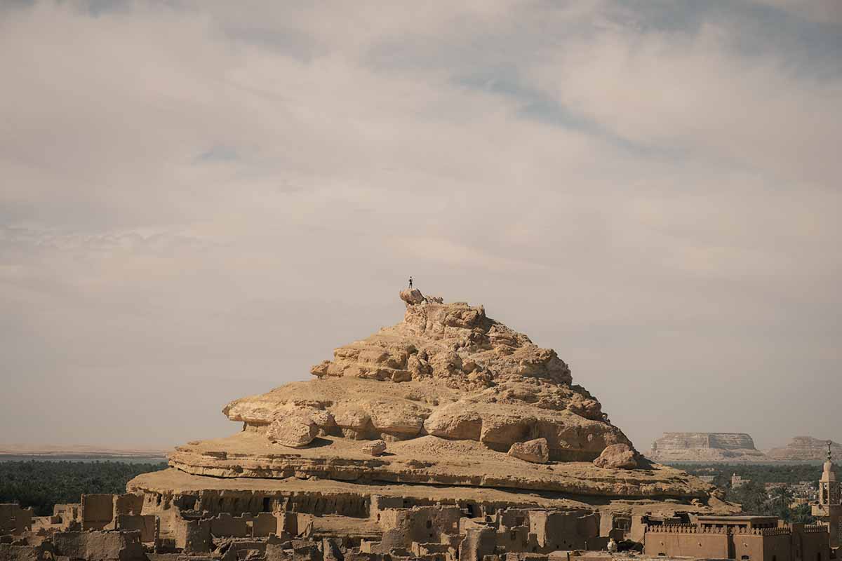 A person standing at the peak of a rocky mountain.