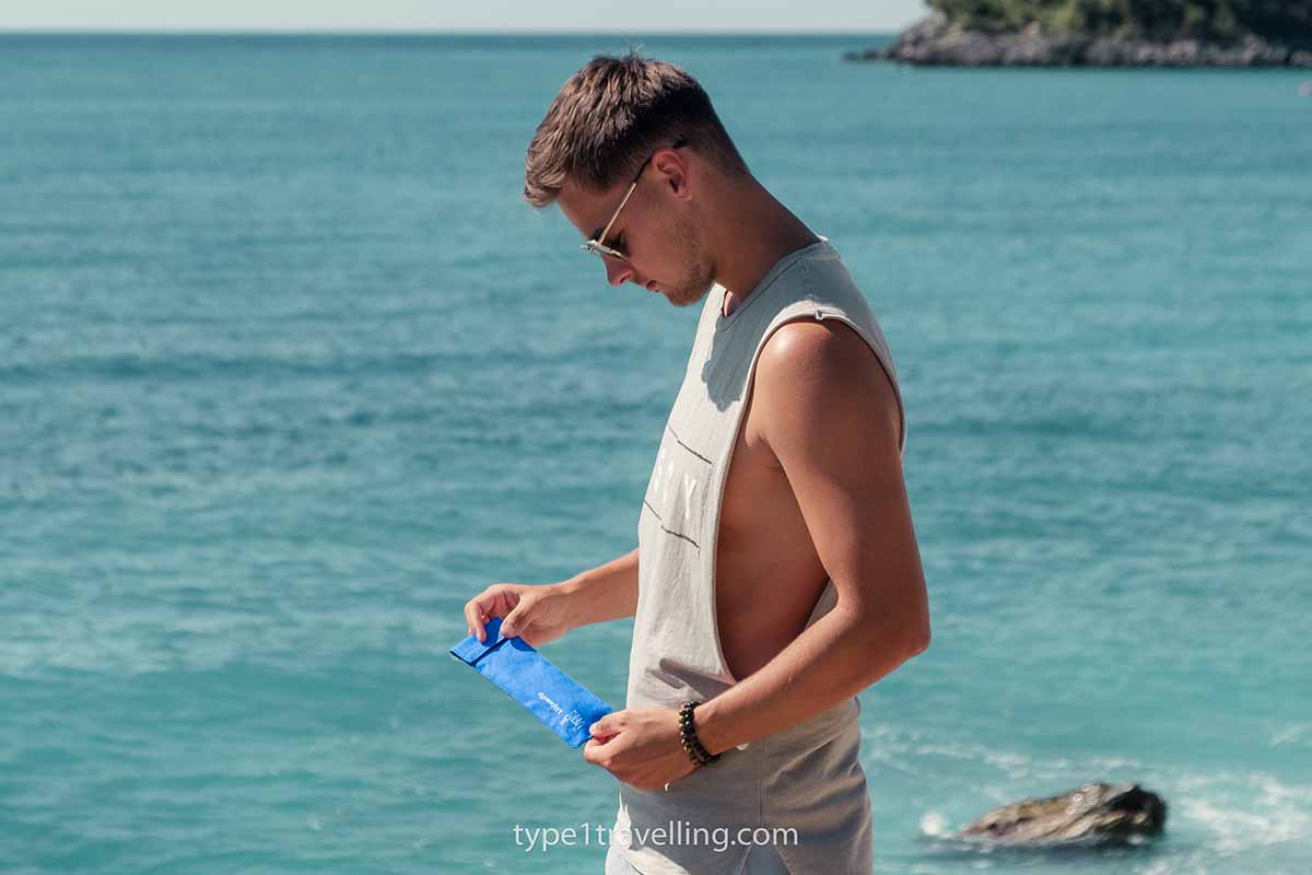 A man holding a 4ALLFAMILY Chiller travel case next to the sea.