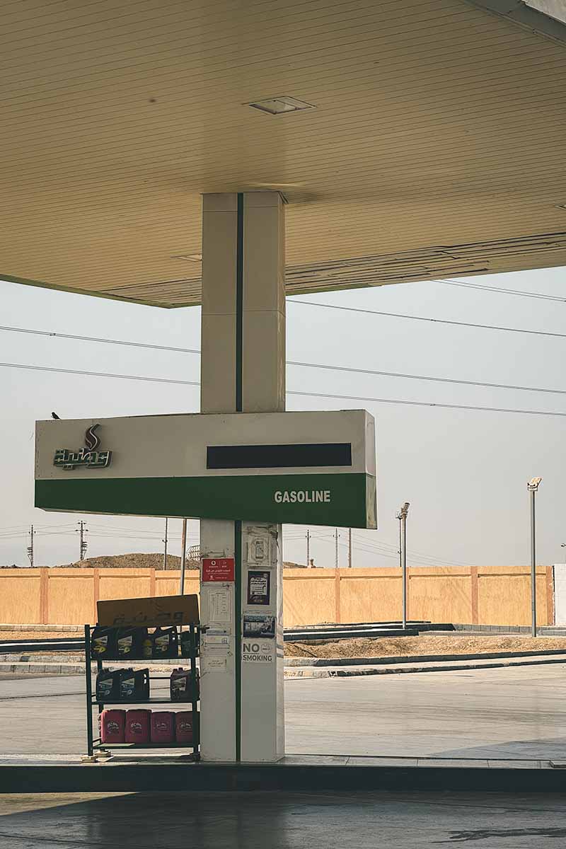 A gasoline pump and a stand of engine oil bottles at a service station.