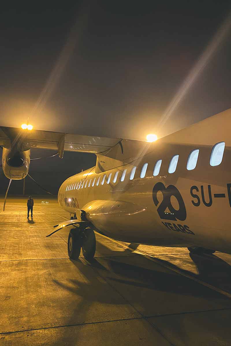 A small Air Cairo airplane parked on the runway at night.