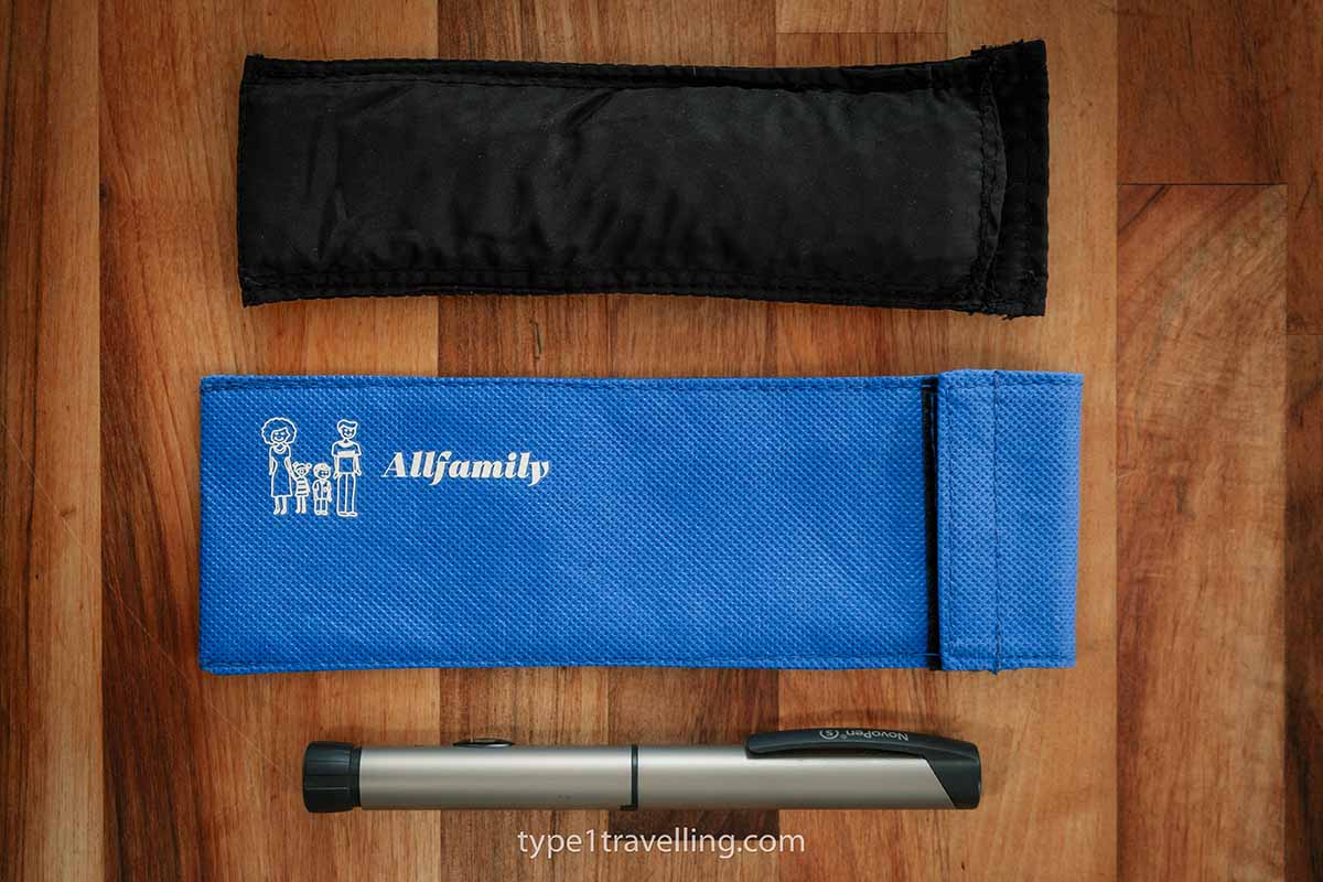 A 4ALLFAMILY Chiller cool pouch and outer wallet and a silver insulin pen lying next to each other on a wooden surface.