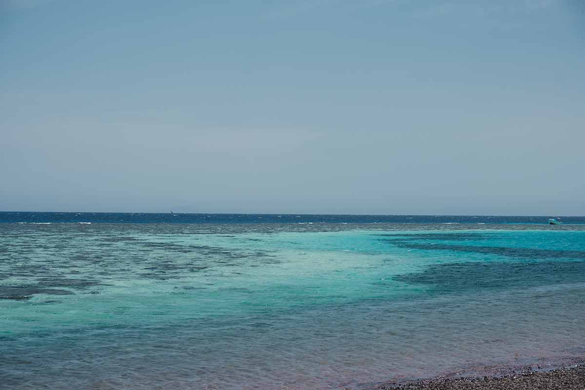 Bright turquoise water covering Dahab's shallow reef, with darker and deeper water in the distance.