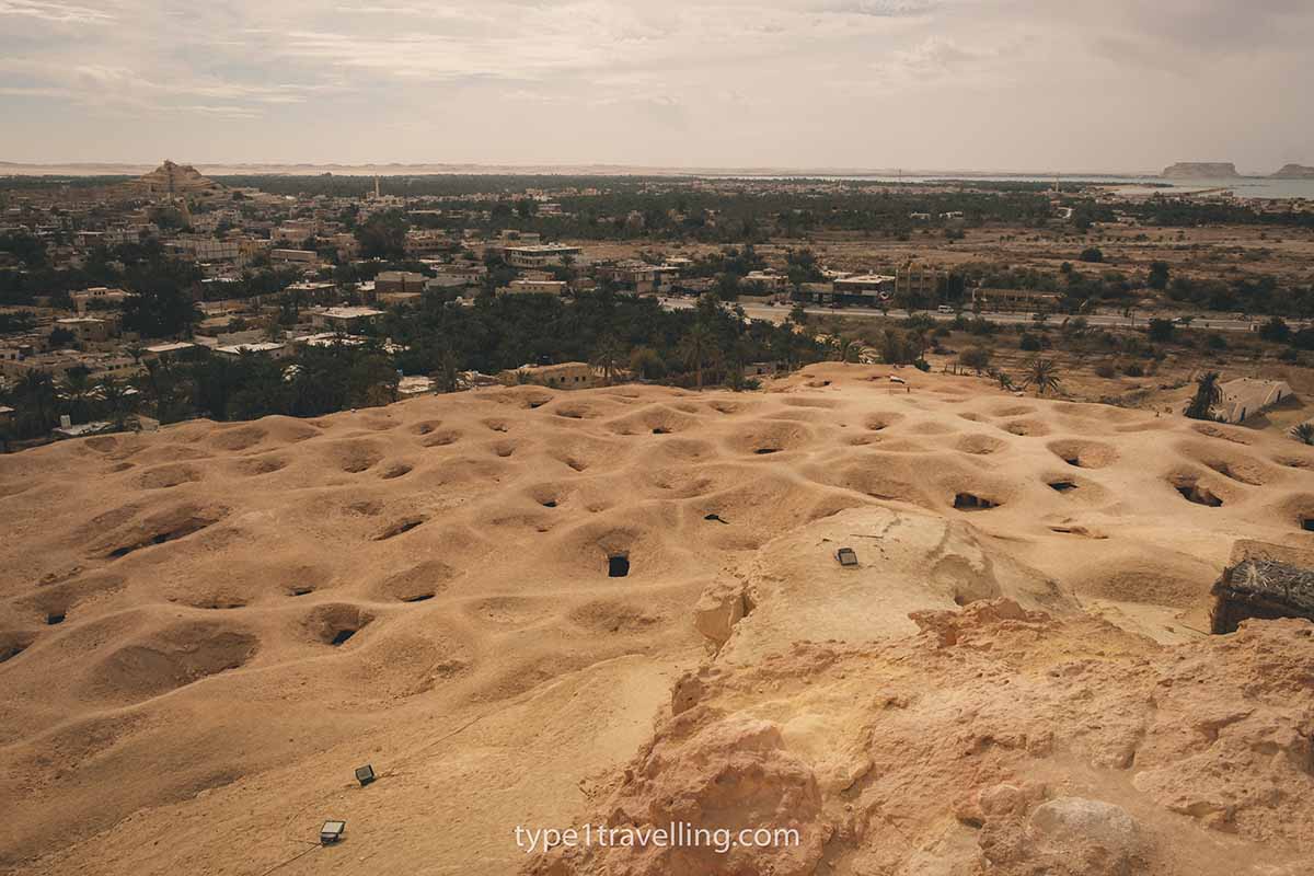 The base of Gabal al Mawta dotted with dark caverns and tombs.