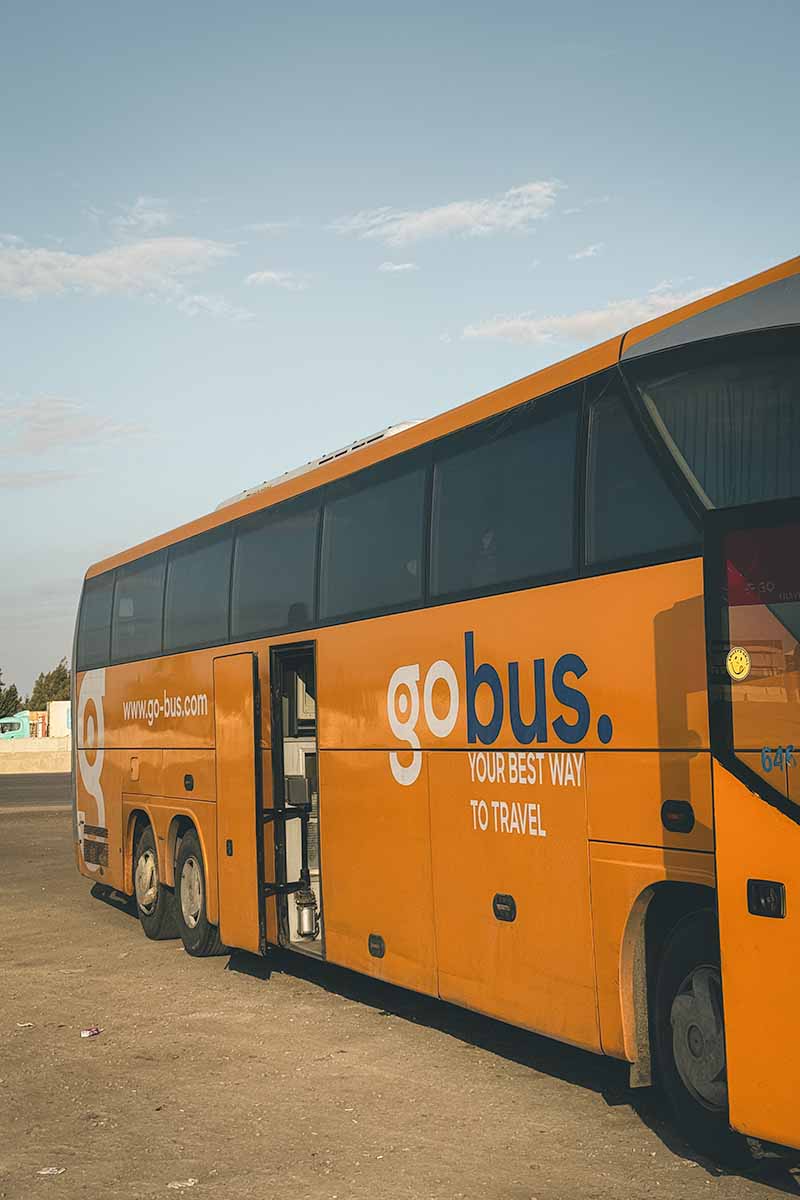 A stationary orange GoBus coach with its passenger doors open.