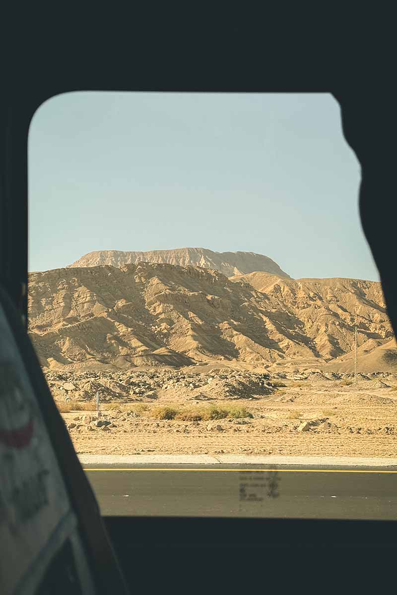 A dry mountain landscape seen through a vehicle window.