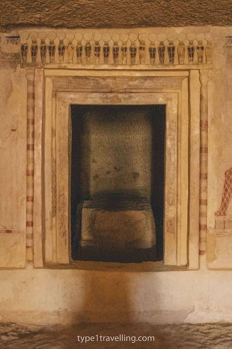 The entrance to a burial chamber in an ancient tomb and a line of painted cobras above.