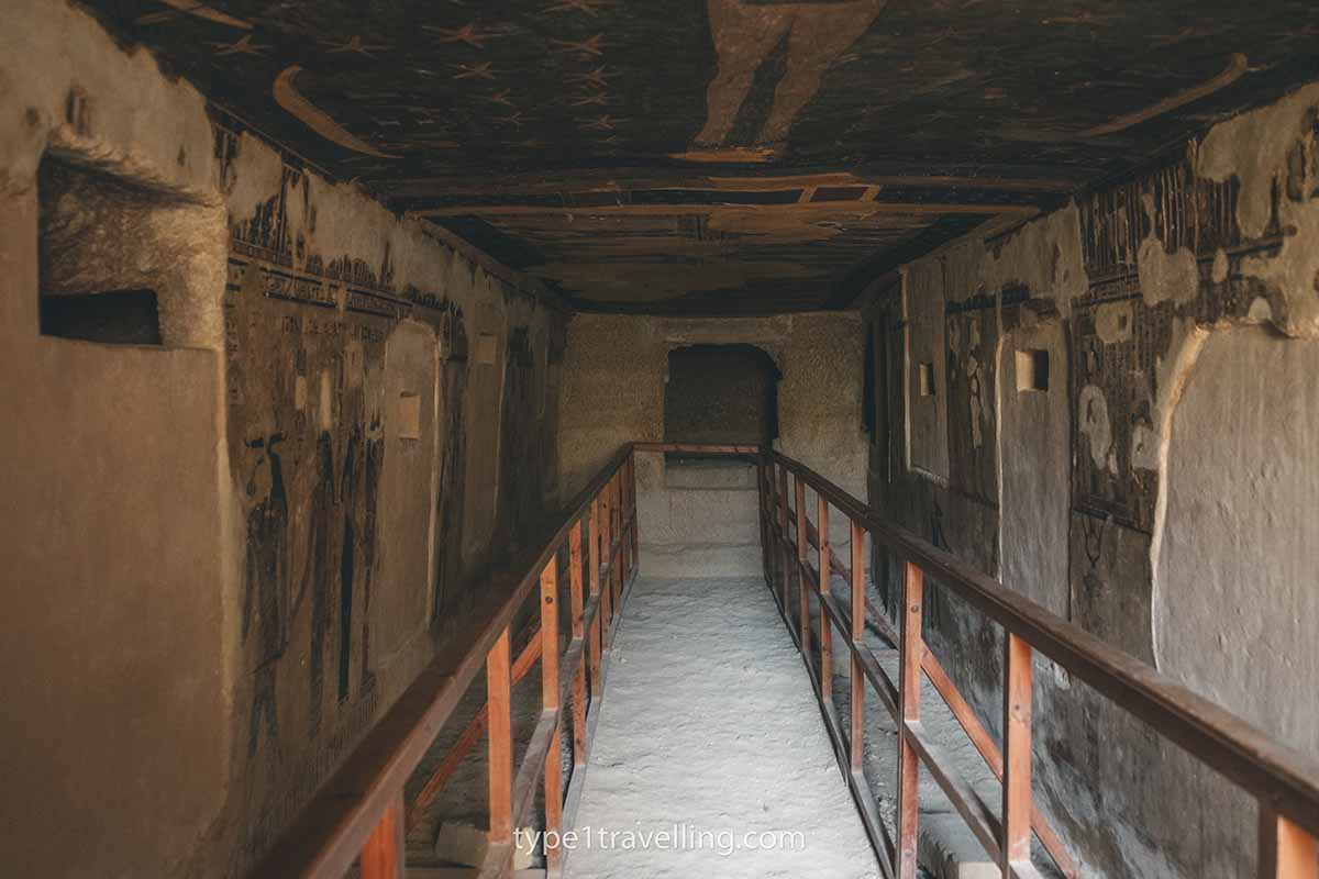 The inside of an ancient tomb with the remains of paintings on the walls and ceiling.