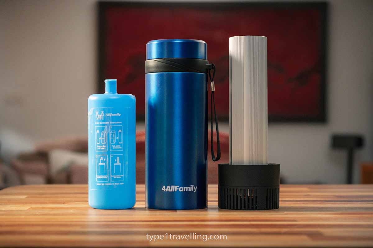 A blue 4ALLFAMILY Voyager insulin cooler, biogel cold pack, and USB lid standing next to each other on a wooden table.