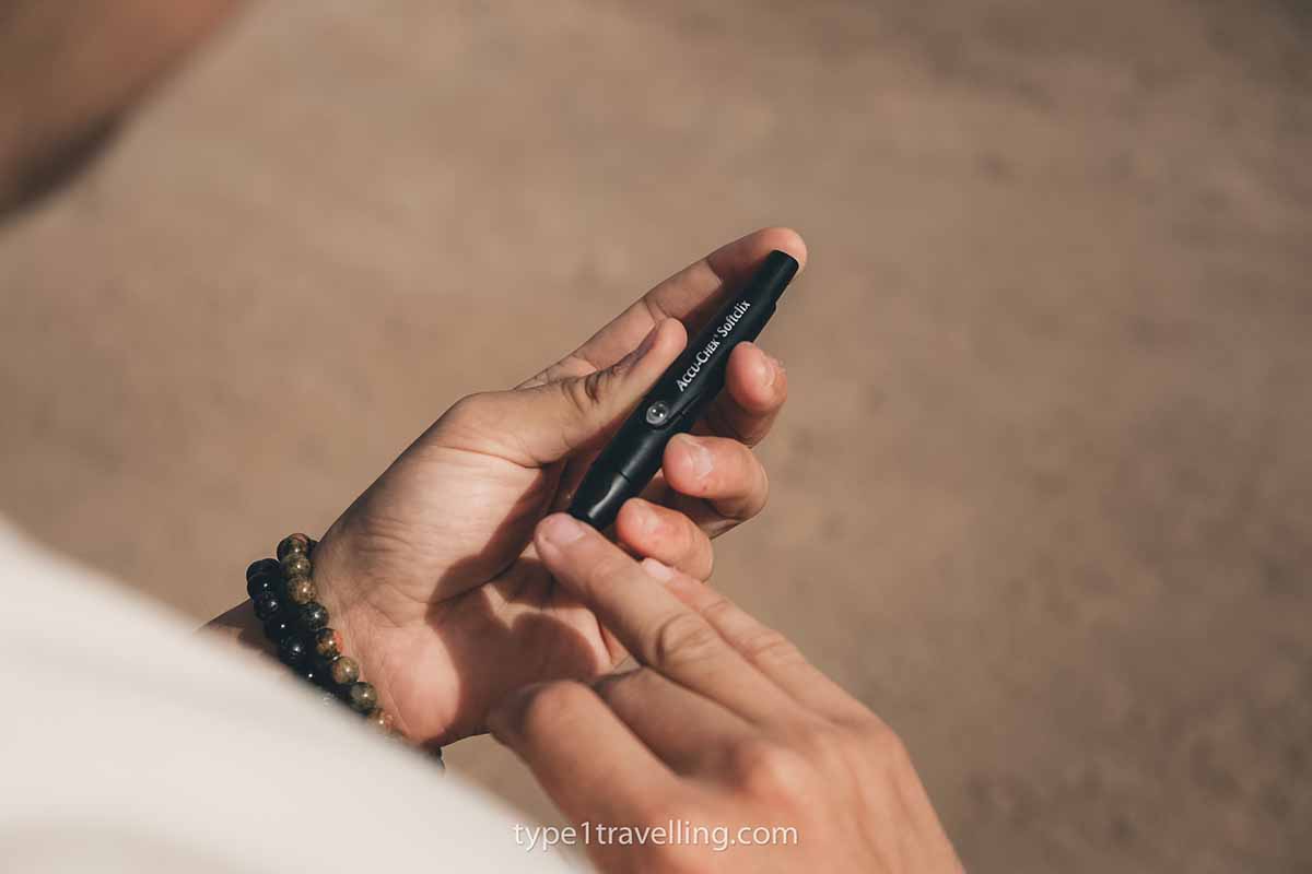 A person pricking their finger to take a blood glucose test with an Accu-Chek Softclix lancet device.