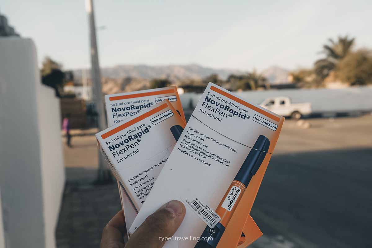 A hand holding three boxes of NovoRapid insulin FlexPens.