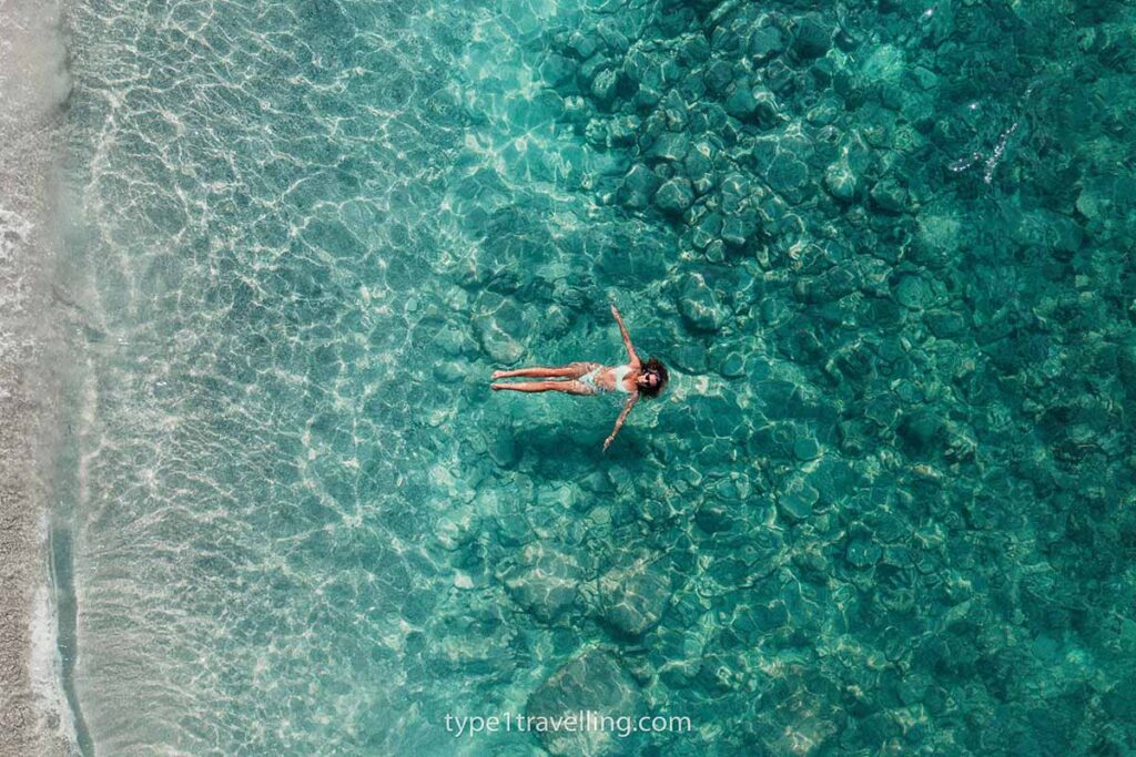 A woman floating on her back in clear turquoise water.