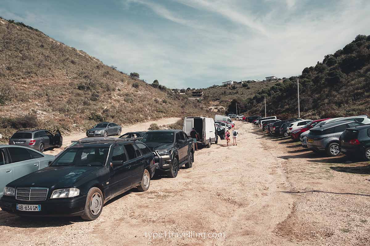 Cars, pickups, and vans parked in Mirror Beach's gravel car park.