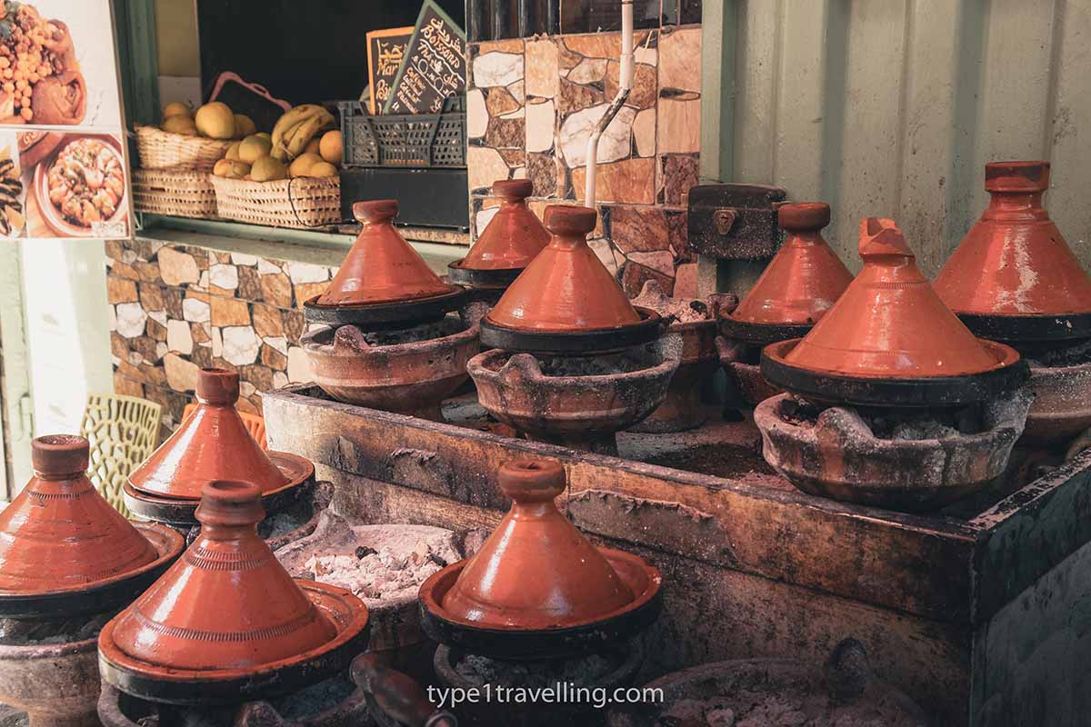 Several tagines being slow cooked in traditional clay pots.