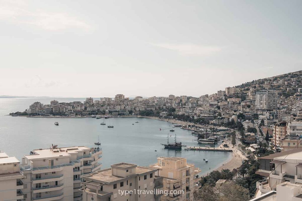 bay-of-saranda The curved bay of Saranda with sprawling apartment buildings and sailboats docked on the promenade.
