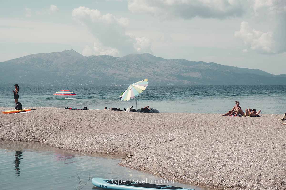 A single parasol and people sunbathing on Bistrica Beach.