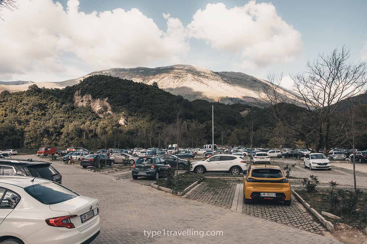 A very busy car park with mountains in the background.