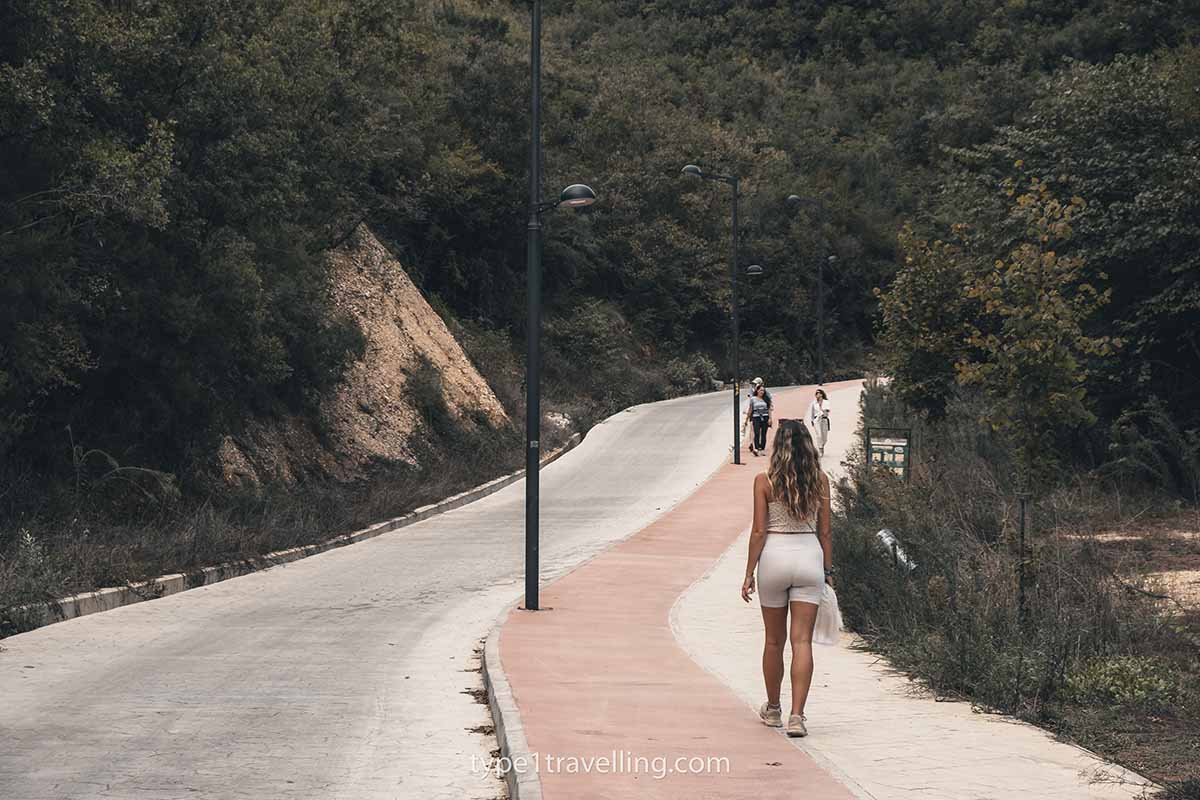 blue-eye-paved-trail A woman walking along a duotone pavement surrounded by greenery and bushes.