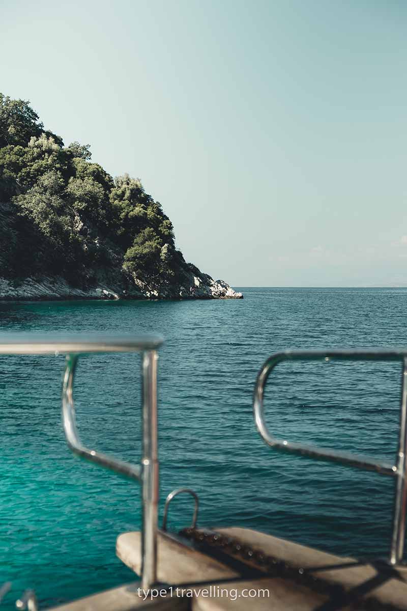 The stern of a boat with the sea and a rocky headland in the background.