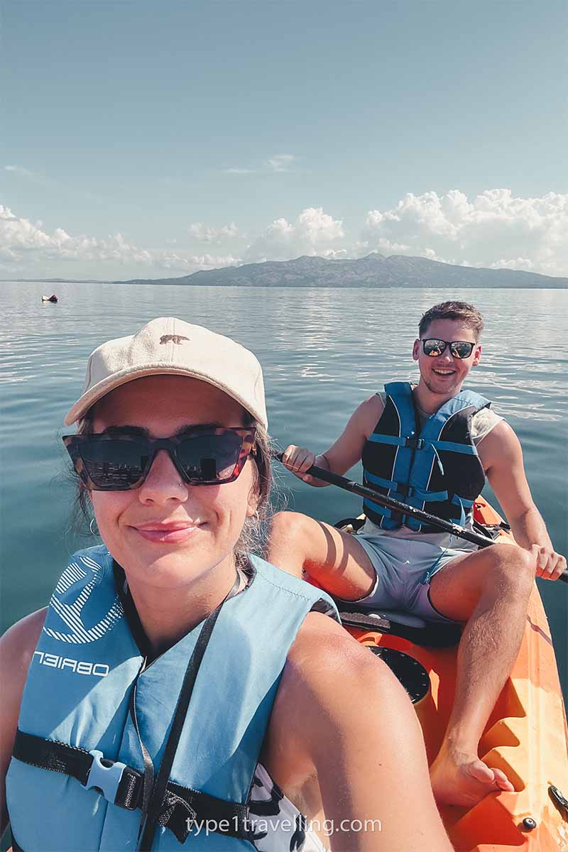 A woman taking a selfie on a kayak with a man sitting behind holding a paddle.