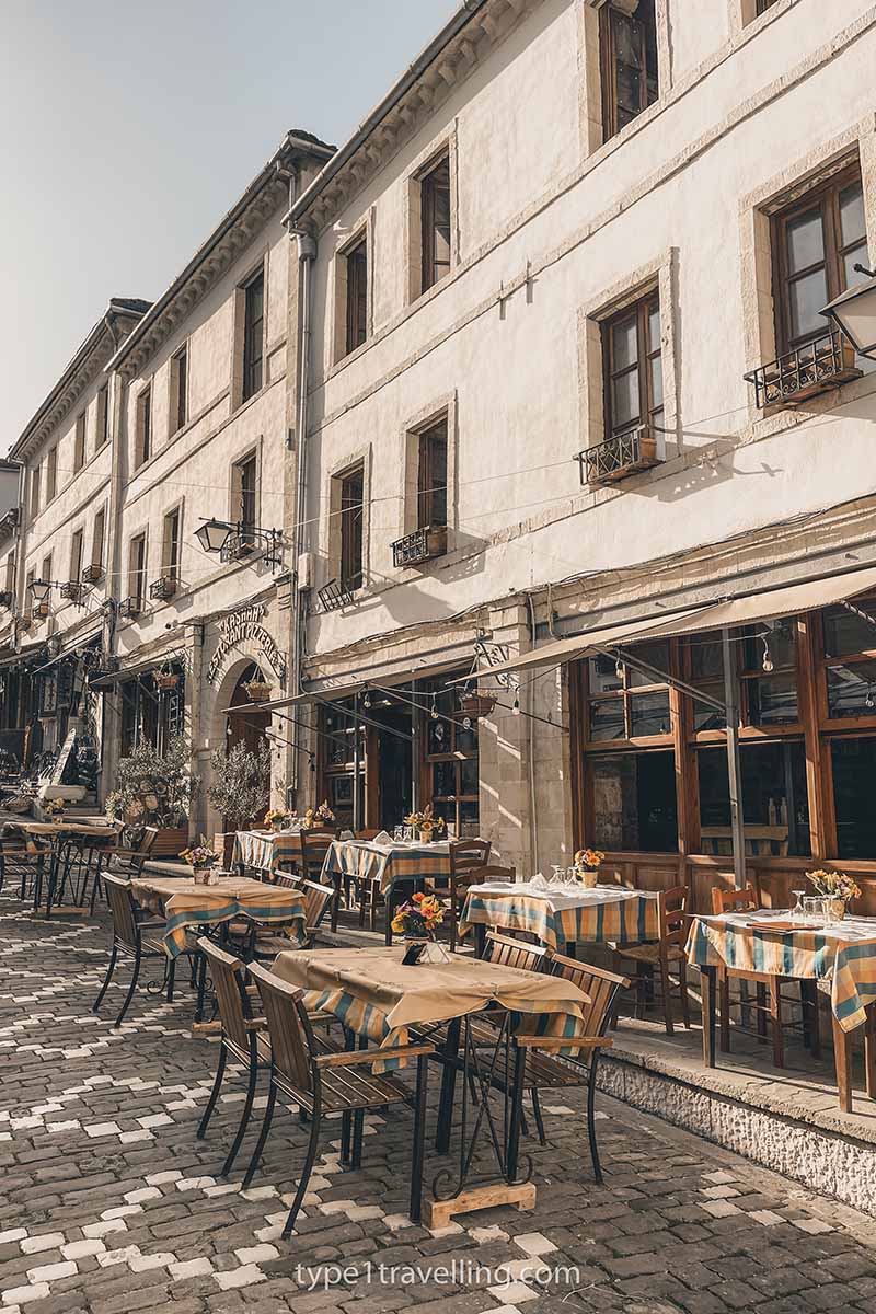 A line of restaurants with outdoor seating on and inclined cobble street.