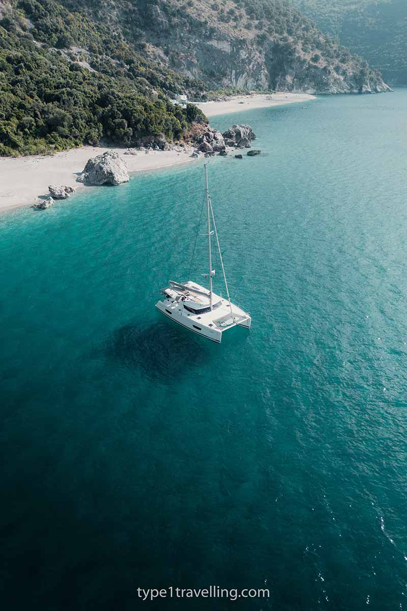 A catamaran boat anchored close to the shore of Kroreza Beach.